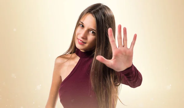 Joven adolescente chica contando cinco en ocre fondo —  Fotos de Stock