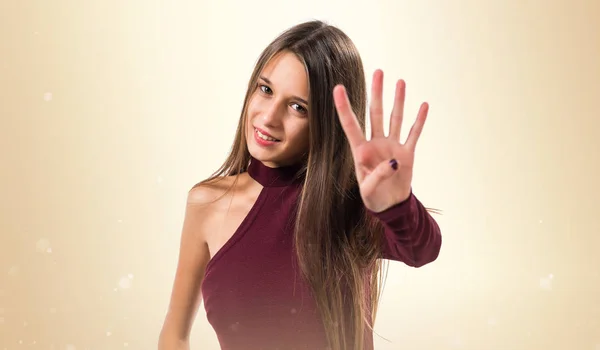 Junges Teenager-Mädchen zählt vier auf ockerfarbenem Hintergrund — Stockfoto