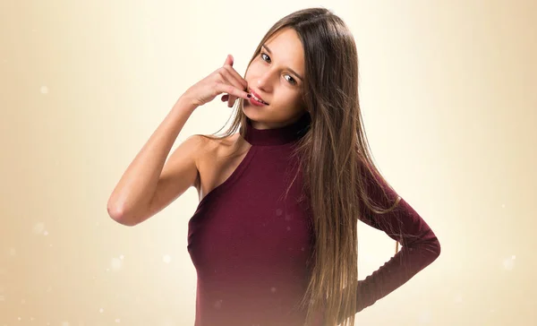 Junges Teenager-Mädchen macht Handygeste auf ockerfarbenem Hintergrund — Stockfoto