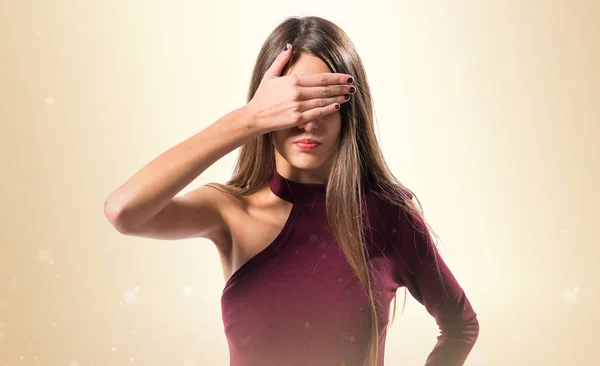 Junges Teenager-Mädchen bedeckt ihre Augen auf ockerfarbenem Hintergrund — Stockfoto