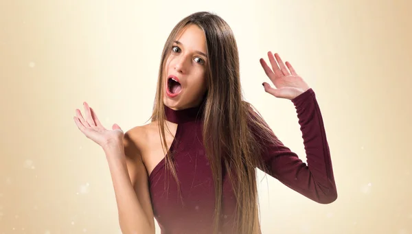 Junges Teenager-Mädchen macht Überraschungsgeste auf ockerfarbenem Hintergrund — Stockfoto