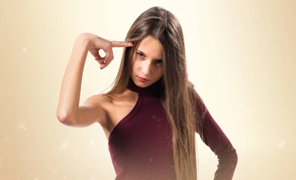 Junges Teenager-Mädchen macht Selbstmordgeste auf ockerfarbenem Hintergrund — Stockfoto