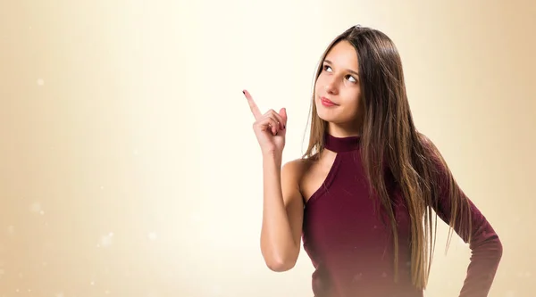 Ung tonåring flicka pekar uppåt på ockra bakgrund — Stockfoto