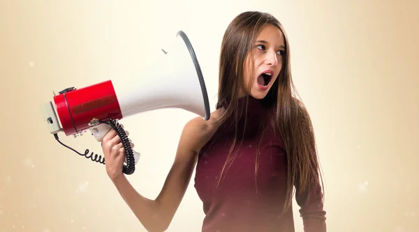 Jovem adolescente gritando por megafone no fundo ocre — Fotografia de Stock