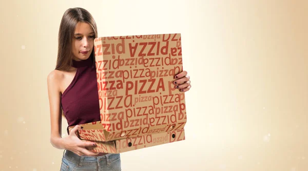 Ung tonåring flicka håller en pizza rutor på ockra bakgrund — Stockfoto