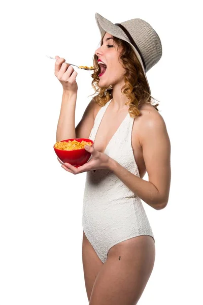 Mulher modelo muito jovem em maiô comendo cereais de uma tigela — Fotografia de Stock