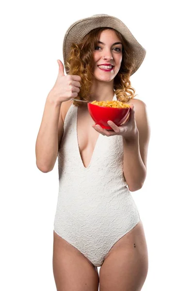 Bella giovane donna modello in costume da bagno mangiare cereali da una ciotola — Foto Stock