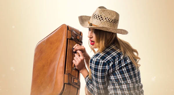 Sexy donna bionda cowgirl con valigia vintage su retro ocra — Foto Stock