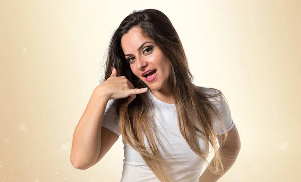 Jovem menina bonita fazendo gesto de telefone no fundo ocre — Fotografia de Stock