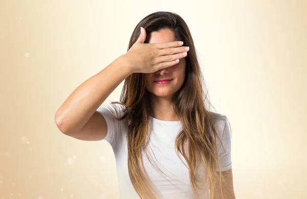 Joven chica bonita cubriendo sus ojos sobre fondo ocre —  Fotos de Stock