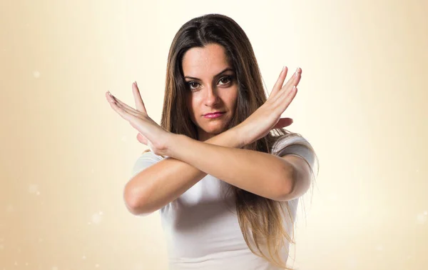 Young pretty girl making NO gesture on ocher background — Stock Photo, Image