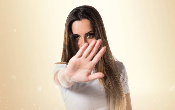 Junges hübsches Mädchen macht Stoppschild auf ockerfarbenem Hintergrund — Stockfoto