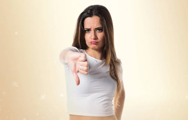 Young pretty girl making bad signal on ocher background — Stock Photo, Image