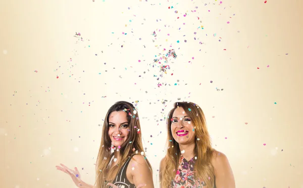 Jovens felizes com confete em uma festa no fundo ocre — Fotografia de Stock