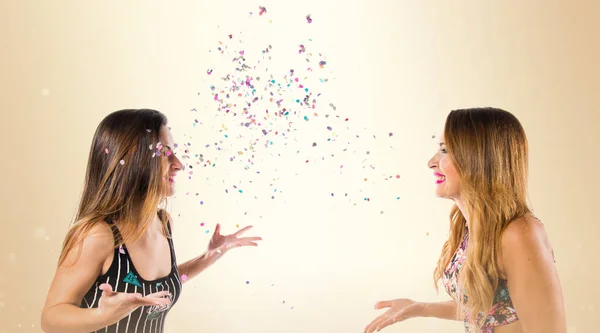 Glückliche junge Mädchen mit Konfetti bei einer Party auf ockerfarbenem Hintergrund — Stockfoto