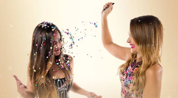 Glückliche junge Mädchen mit Konfetti bei einer Party auf ockerfarbenem Hintergrund — Stockfoto