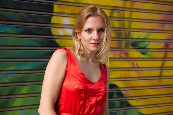 Hübsche blonde Frau auf der Straße mit rotem Kleid — Stockfoto