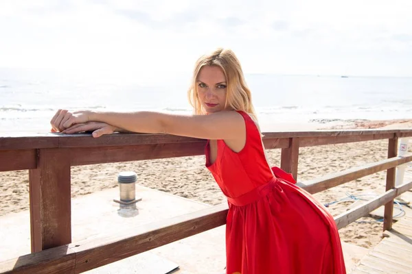 Όμορφη ξανθιά γυναίκα με κόκκινο φόρεμα για την παραλία — Φωτογραφία Αρχείου