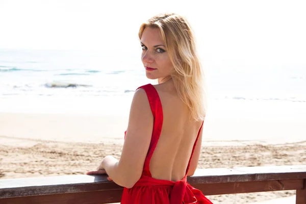 Όμορφη ξανθιά γυναίκα με κόκκινο φόρεμα για την παραλία — Φωτογραφία Αρχείου