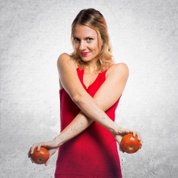 Krásná blondýna žena držící rajčata na podklad s texturou — Stock fotografie