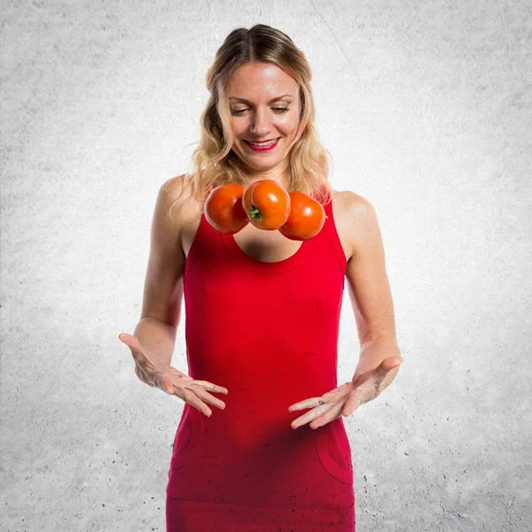 Schöne blonde Frau hält Tomaten auf strukturiertem Hintergrund — Stockfoto