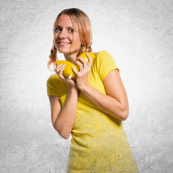 Hermosa mujer rubia sosteniendo limones sobre fondo texturizado — Foto de Stock