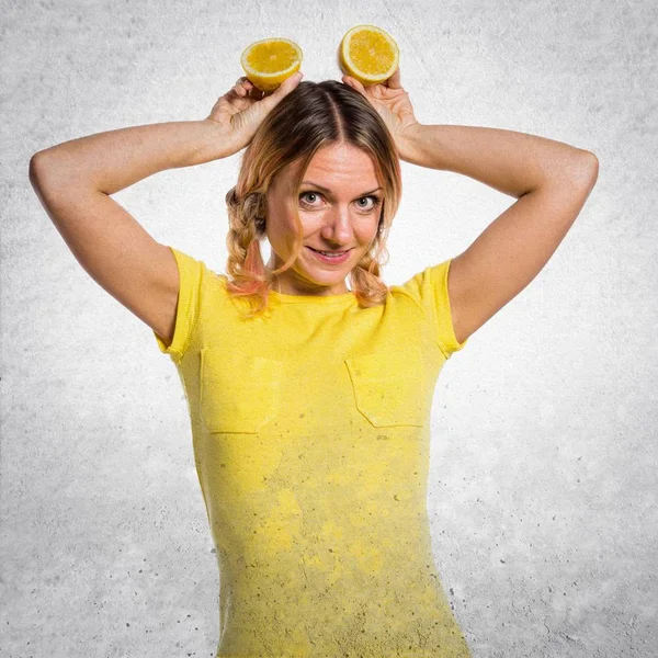 Hermosa mujer rubia sosteniendo limones sobre fondo texturizado — Foto de Stock
