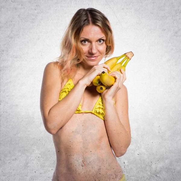 Mulher loira bonita de biquíni segurando bananas no bac texturizado — Fotografia de Stock