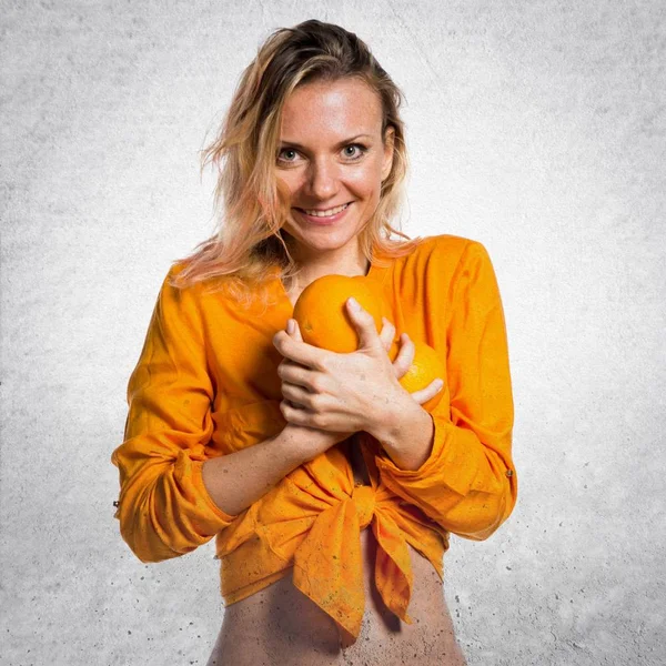 Portakal dokulu arka plan üzerinde tutan güzel sarışın kadın — Stok fotoğraf