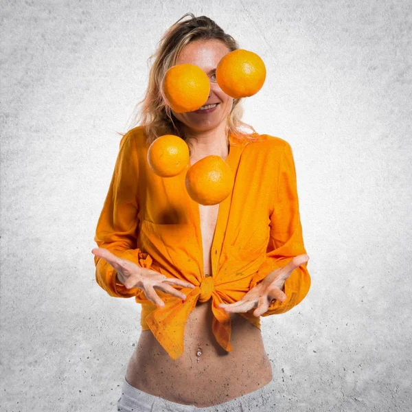 Bella donna bionda che tiene arance su sfondo strutturato — Foto Stock