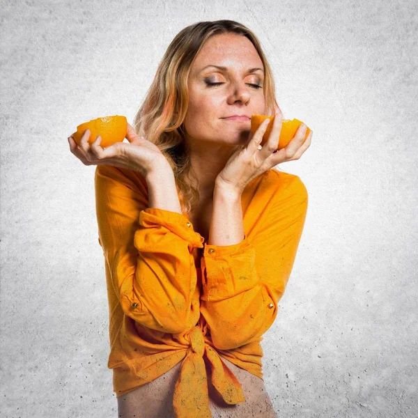 Schöne blonde Frau hält Orangen auf strukturiertem Hintergrund — Stockfoto