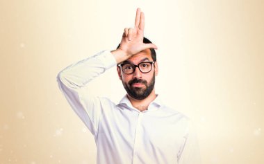 Koyu sarı arka plan üzerinde aptal tabelayı yapıyor gözlüklü yakışıklı adam