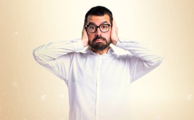 Kulakları koyu sarı zemin üzerine kapsayan gözlüklü yakışıklı adam