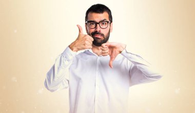 İyi-kötü işareti üzerinde koyu sarı backgrou yapma gözlüklü yakışıklı adam