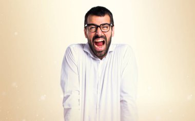 Koyu sarı zemin üzerine bağırarak gözlüklü kızgın yakışıklı adam