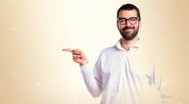 Gözlüklü lateral okra backg üzerinde işaret eden yakışıklı adam