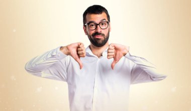 Koyu sarı zemin üzerine kötü sinyal yapıyor gözlüklü yakışıklı adam