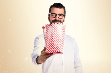 Popcorns koyu sarı arka plan üzerinde yemek gözlüklü yakışıklı adam