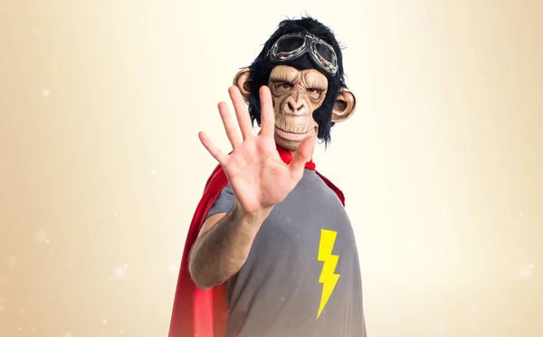 Superhero monkey man counting five on ocher background