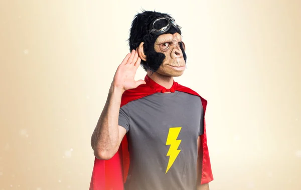 Supereroe scimmia uomo ascoltando qualcosa su sfondo ocra — Foto Stock