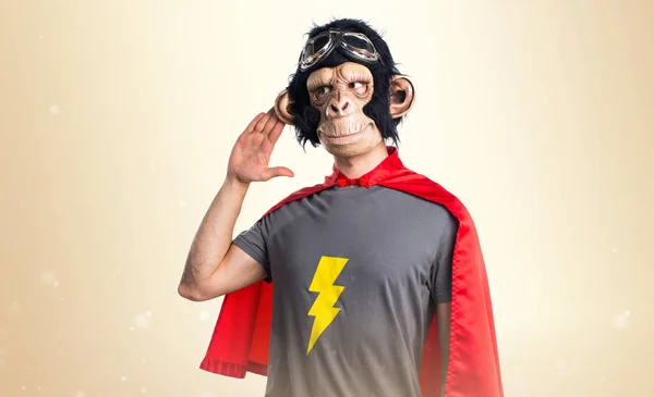 Superhero monkey man listening something on ocher background