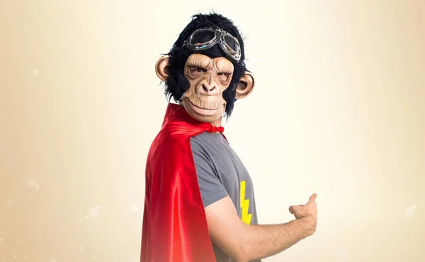 Υπερήρωα μαϊμού άνθρωπος δείχνοντας πίσω στο φόντο ώχρα — Φωτογραφία Αρχείου
