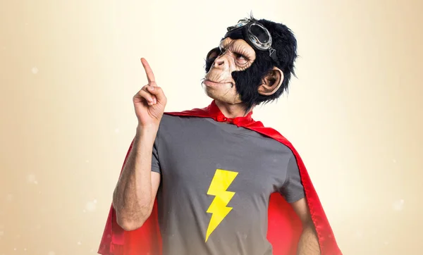 Υπερήρωα μαϊμού άνθρωπος δείχνει προς τα επάνω σε φόντο ώχρα — Φωτογραφία Αρχείου