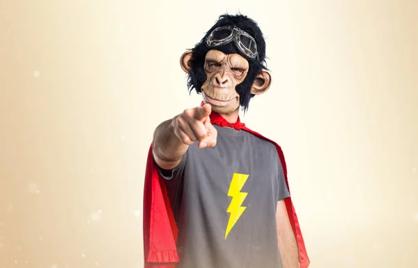 Superhero monkey man pointing to the front on ocher background