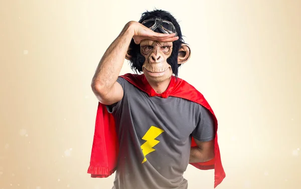 Superhero monkey man showing something on ocher background