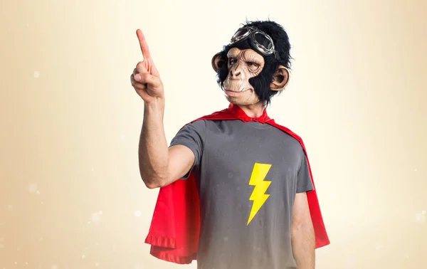 Superhero monkey man touching on transparent screen on ocher bac