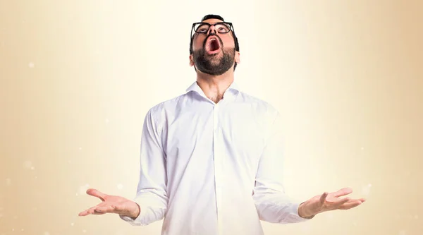 Hombre guapo con gafas en posición zen sobre fondo ocre — Foto de Stock