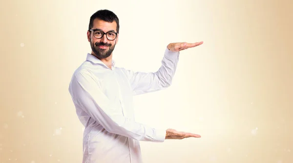 Stilig man med glasögon höll något på ockra bakgrund — Stockfoto