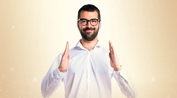 Knappe man met bril houden iets over okergeel achtergrond — Stockfoto