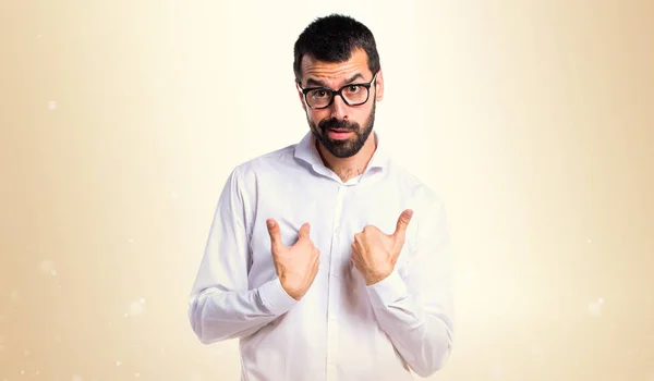 Pohledný muž s brýlemi dělá gesto překvapení na okrové pozadí — Stock fotografie